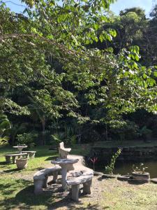 un parc avec des bancs, un étang et des arbres dans l'établissement Casa 2, à Praia Grande