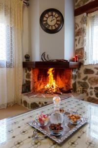 a living room with a fireplace with a clock at Petrino House Lasithi in Agios Georgios