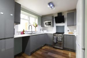 cocina con armarios grises, fregadero y fogones en Spacious 4-Bed Family House, en Portsmouth