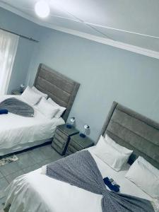President Guest Lodge في لويس تريشارد: سريرين في غرفة فندق مع سريرين sidx sidx