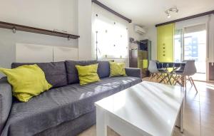 a living room with a gray couch with yellow pillows at Nice Apartment In Moncofa Playa With Outdoor Swimming Pool in Moncófar