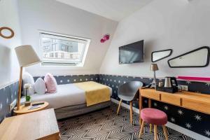 Cette chambre comprend un lit, un bureau et des chaises. dans l'établissement Hôtel Augustin - Astotel, à Paris