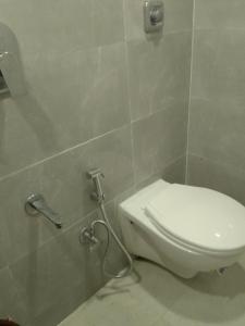 a bathroom with a toilet in a tiled wall at Kufa PG Dormitory in Mumbai