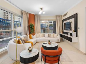 a living room with a white couch and orange chairs at Charming & Vibrant 1Bedroom In Marina Quay in Dubai