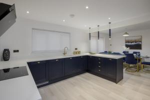 a kitchen with blue cabinets and a dining room at Belverdale by STAMP SA in Blackpool