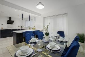 a dining room with a glass table and blue chairs at Belverdale by STAMP SA in Blackpool