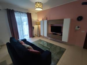 a living room with a blue couch and a tv at St Julians - Balluta 2 bedroom apartment in St Julian's
