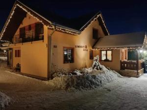 a house covered in snow at night with lights at Garni Limbový Dvor in Vrbov
