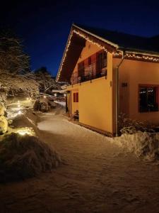 a house with lights on it in the snow at Garni Limbový Dvor in Vrbov