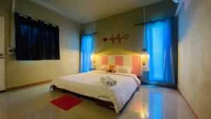 um quarto com uma grande cama branca com cortinas azuis em พิมานอินทร์ รีสอร์ท em Ban Phang Khwang Tai