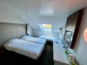 a small room with two beds and a television at Campanile Montargis - Amilly in Amilly