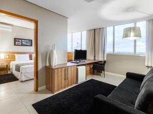 a hotel room with a bed and a desk with a television at Days Inn by Wyndham Linhares in Linhares