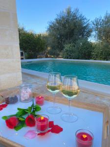 two glasses of wine and candles on a table next to a swimming pool at La Mignola in Fasano