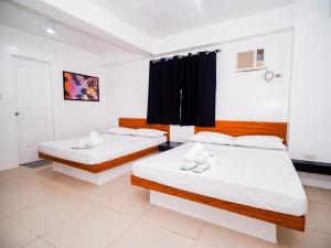 two beds in a room with black curtains at CJS Boracay Joint in Boracay