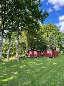 にあるJõeallika kämpingの緑地の木々が植わる赤い小屋2室