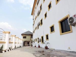 an empty courtyard of a white building with potted plants at MOSANG HOTELS & SUITES in Aba