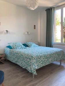 a bedroom with a bed with a blue comforter and a window at La maison d’Alice in Aix-les-Bains
