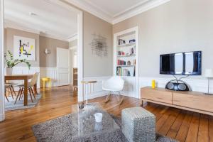 ein Wohnzimmer mit einem TV und einem Tisch in der Unterkunft Appartement calme avec cachet (20 min de Paris) in Maisons-Laffitte