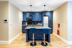 a blue kitchen with blue cabinets and blue stools at Colourful Studio Near Clapham Common! in London