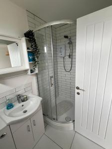 a white bathroom with a shower and a sink at 288, Belle Aire, Hemsby - Beautifully presented two bed chalet, sleeps 5, pet friendly, close to beach! in Hemsby