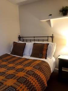 a bedroom with a bed with a blanket and pillows at Bryn Pistyll 2 bedrooms Bethesda in Llanllechid