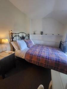 a bedroom with a bed with a plaid blanket at Bryn Pistyll 2 bedrooms Bethesda in Llanllechid