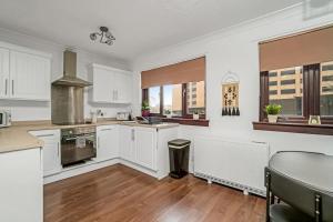a kitchen with white cabinets and a table at BrightCentral Apartment With Parking in Glasgow