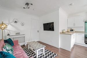 uma sala de estar com um sofá rosa e uma cozinha em BrightCentral Apartment With Parking em Glasgow