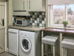 uma cozinha com uma máquina de lavar roupa e um micro-ondas em Beck Cottage em Thirsk