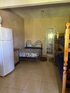 Cette chambre dispose d'un réfrigérateur et d'un lit. dans l'établissement Pousada Recanto do Zeca casa 3, à Praia Grande