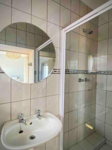 W łazience znajduje się umywalka oraz prysznic z lustrem. w obiekcie Beachfront 3 bedroom house w mieście Hentiesbaai