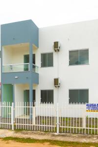 a white building with a fence in front of it at Residencial Sales in Guaibim
