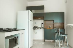 a kitchen with green cabinets and a white refrigerator at Residencial Sales in Guaibim