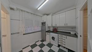 a kitchen with white cabinets and a checkered floor at Casa Angela in Santoña