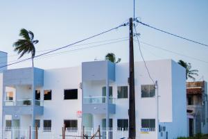 a white building with palm trees in front of it at Residencial Sales in Guaibim