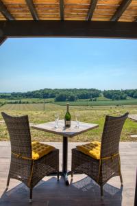 una mesa con 2 sillas y una botella de vino en L'Annexe Coté Castagne du Domaine des Hauts de Rouquette, en Eymet