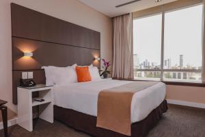 um quarto de hotel com uma cama grande e uma janela grande em Paseo La Galería Hotel & Suites em Assunção