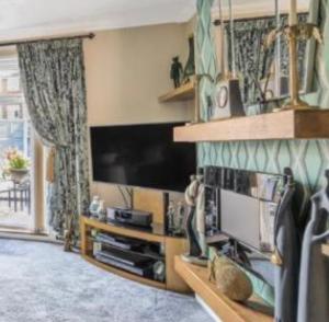 een woonkamer met een flatscreen-tv en een televisie bij A Perfect Two Bedroom House for a Family Stay in Havering atte Bower