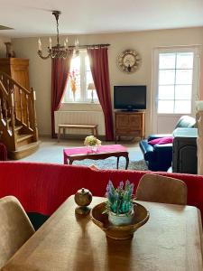 Gîte Sur puremont في Burdinne: غرفة معيشة مع أريكة حمراء وطاولة
