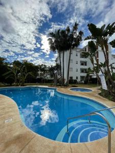 einem großen blauen Pool mit Palmen und einem Gebäude in der Unterkunft Cozy apartment in Costa del Sol in Mijas Costa