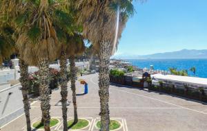 a row of palm trees next to the ocean at Gorgeous Home In Reggio Calabria With Kitchen in Reggio di Calabria