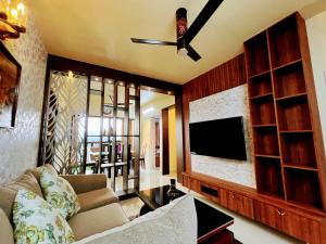 a living room with a couch and a flat screen tv at Chic 2BR Haven in the midst of greenery. in Mangalore