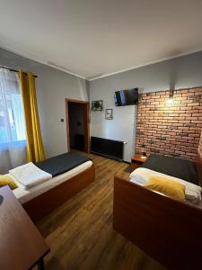 a hotel room with two beds and a brick wall at Hotel Nenufar Premium in Kościan