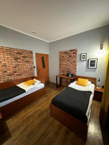 una camera con due letti e un muro di mattoni di Hotel Nenufar Premium a Kościan