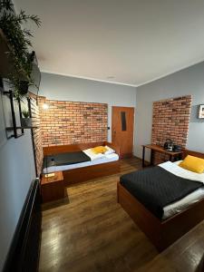 sypialnia z 2 łóżkami i ceglaną ścianą w obiekcie Hotel Nenufar Premium w mieście Kościan