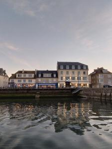 un groupe de bâtiments à côté d'une masse d'eau dans l'établissement Le Grand Hôtel de la Marine, à Port-en-Bessin-Huppain