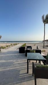 una playa con mesas, sillas y una palmera en Hawana salalah Apartment Acacia en Salalah
