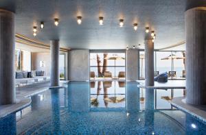 a pool in a hotel with tables and umbrellas at Cora Hotel & Spa in Afitos