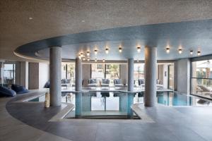 a swimming pool in a house with chairs and tables at Cora Hotel & Spa in Afitos