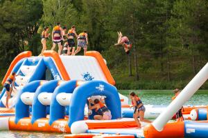a group of people jumping off an inflatable raft at Mobil Home XXL 4 chambres - Camping Les Lacs d'Armagnac in Bretagne-dʼArmagnac